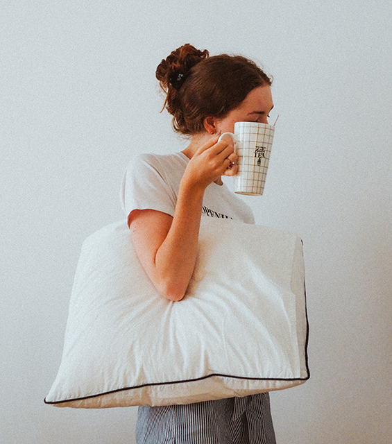 woman with a sleep issue holding a coffee mug and a pillow