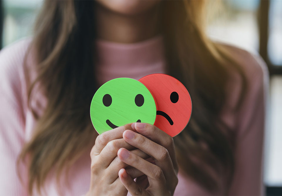 Woman holding happy and sad faces