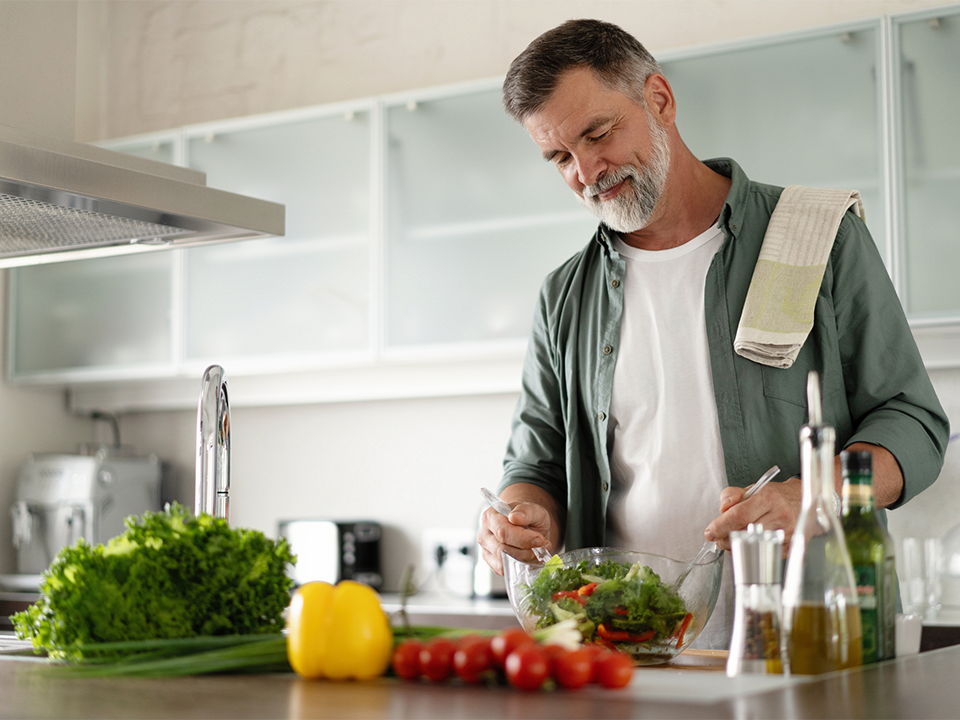 Man in kitchen making a salad